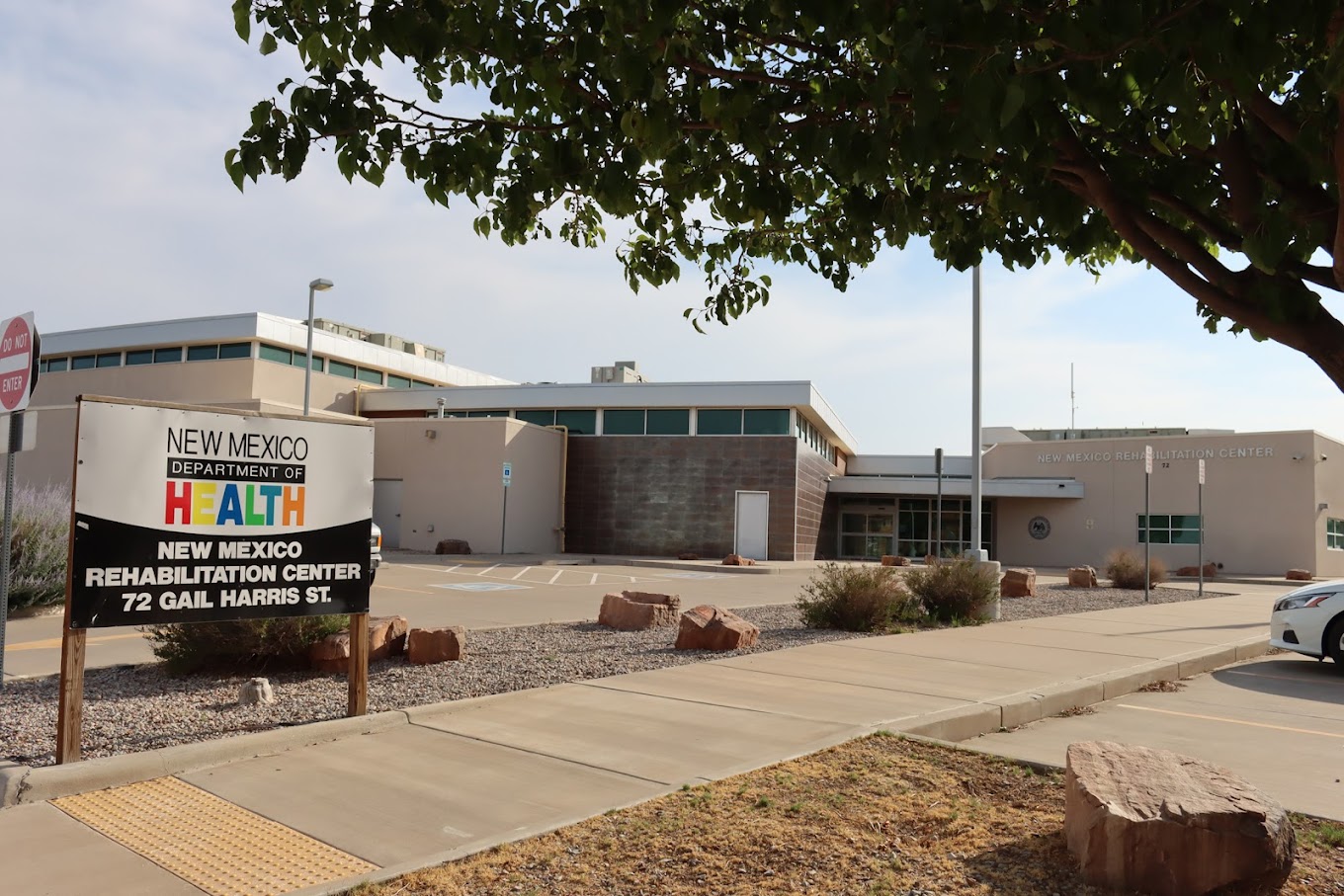 Facility entrance with NMDOH sign and tree in foreground