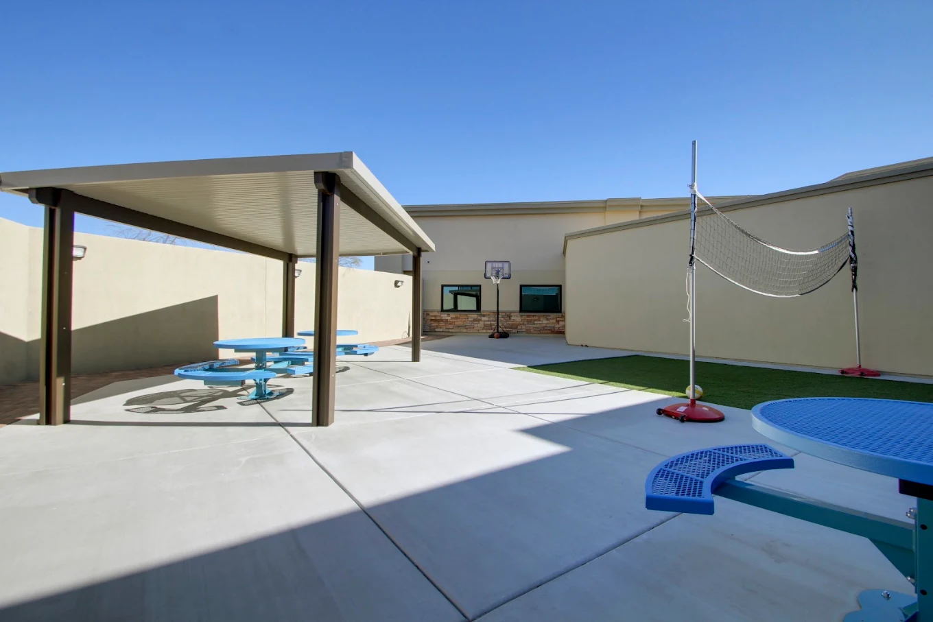 Outdoor recreation area with volleyball net and basketball hoop.