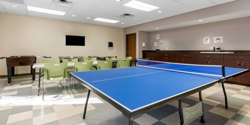  A bright, inviting recreation room featuring a ping-pong table, foosball, and seating, ideal for relaxation and social activities.