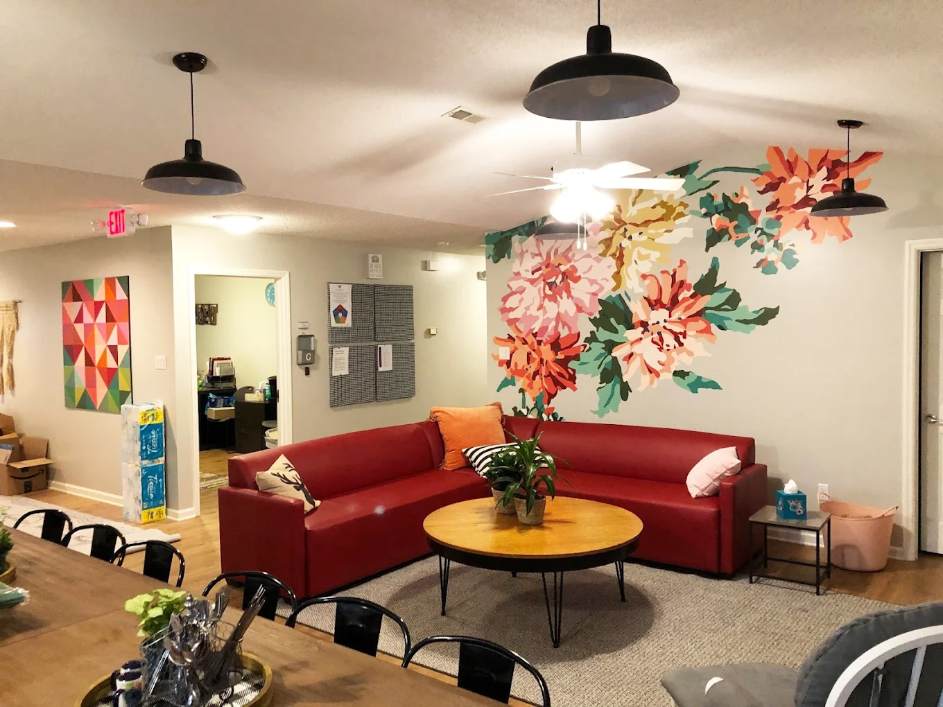 Living room with red sectional and floral wall mural