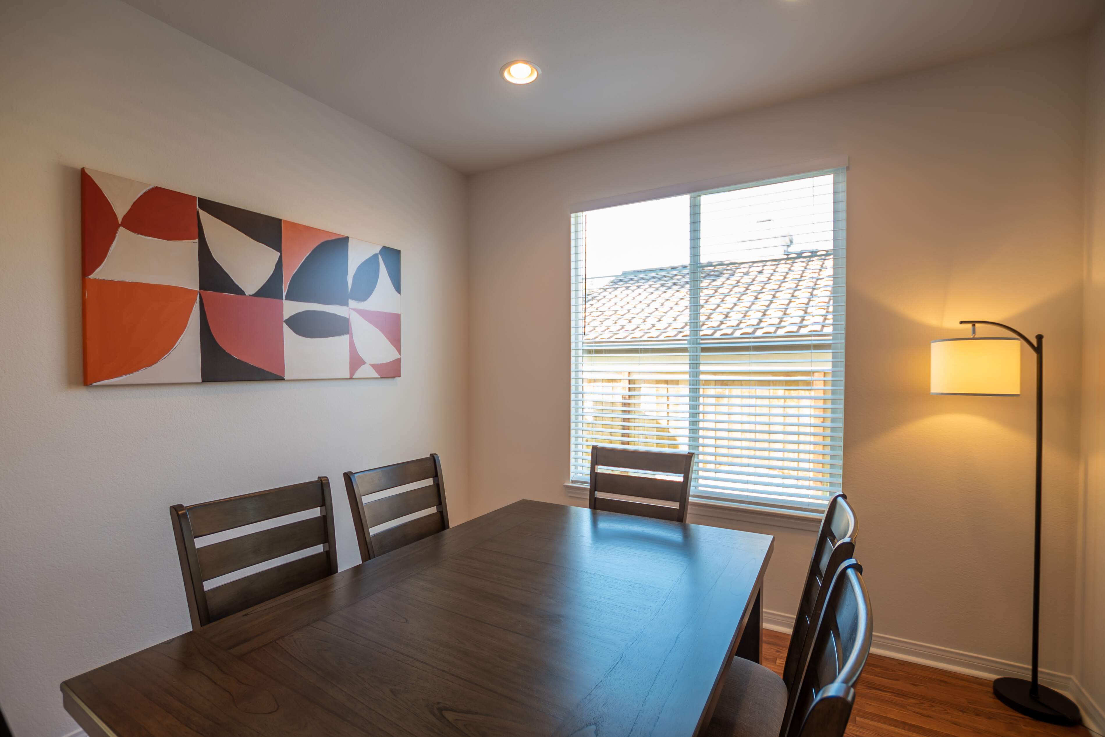 Dining area with four chairs and modern artwork