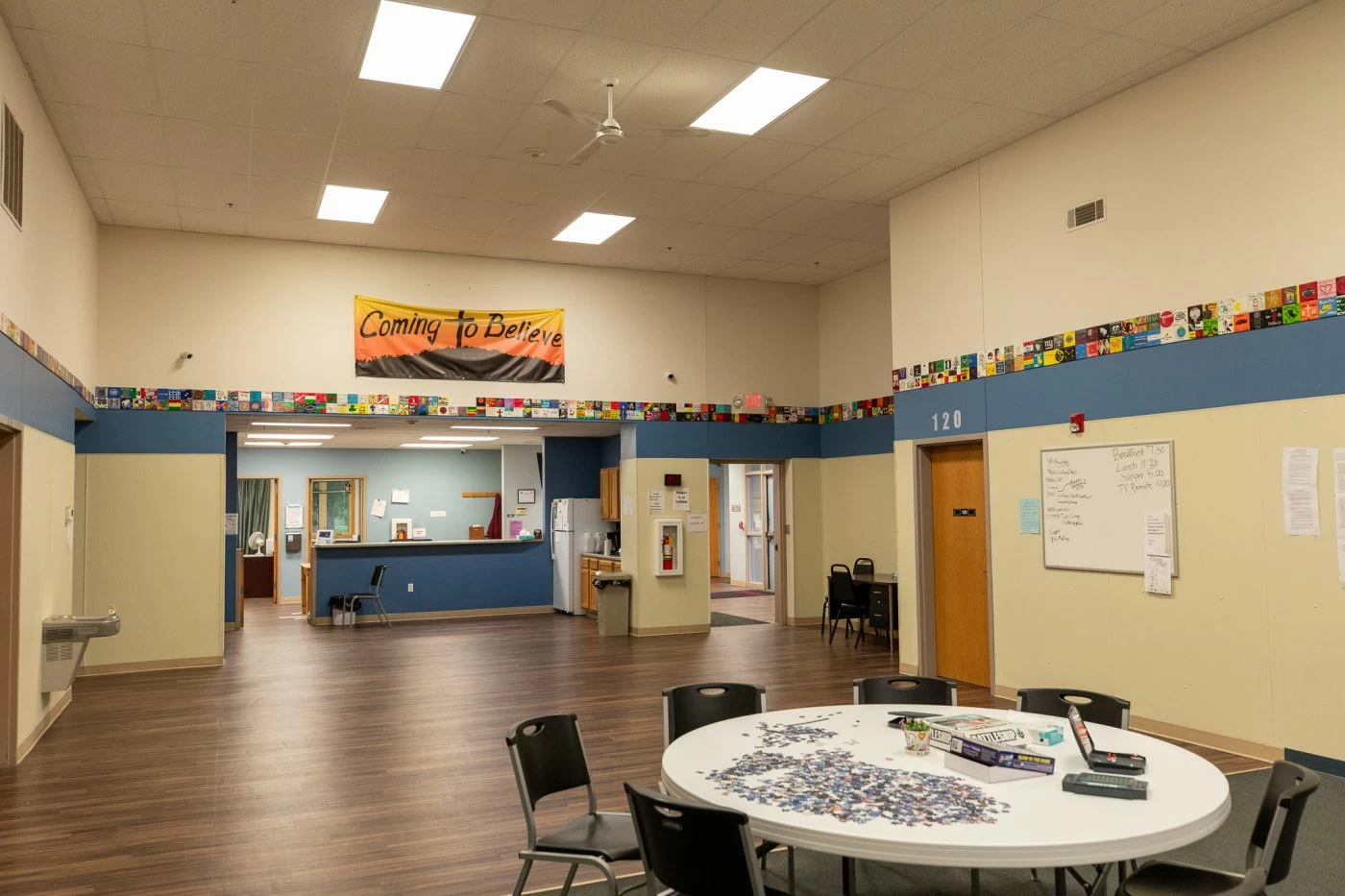 Spacious residential common area with tables, seating, and reception desk at treatment center