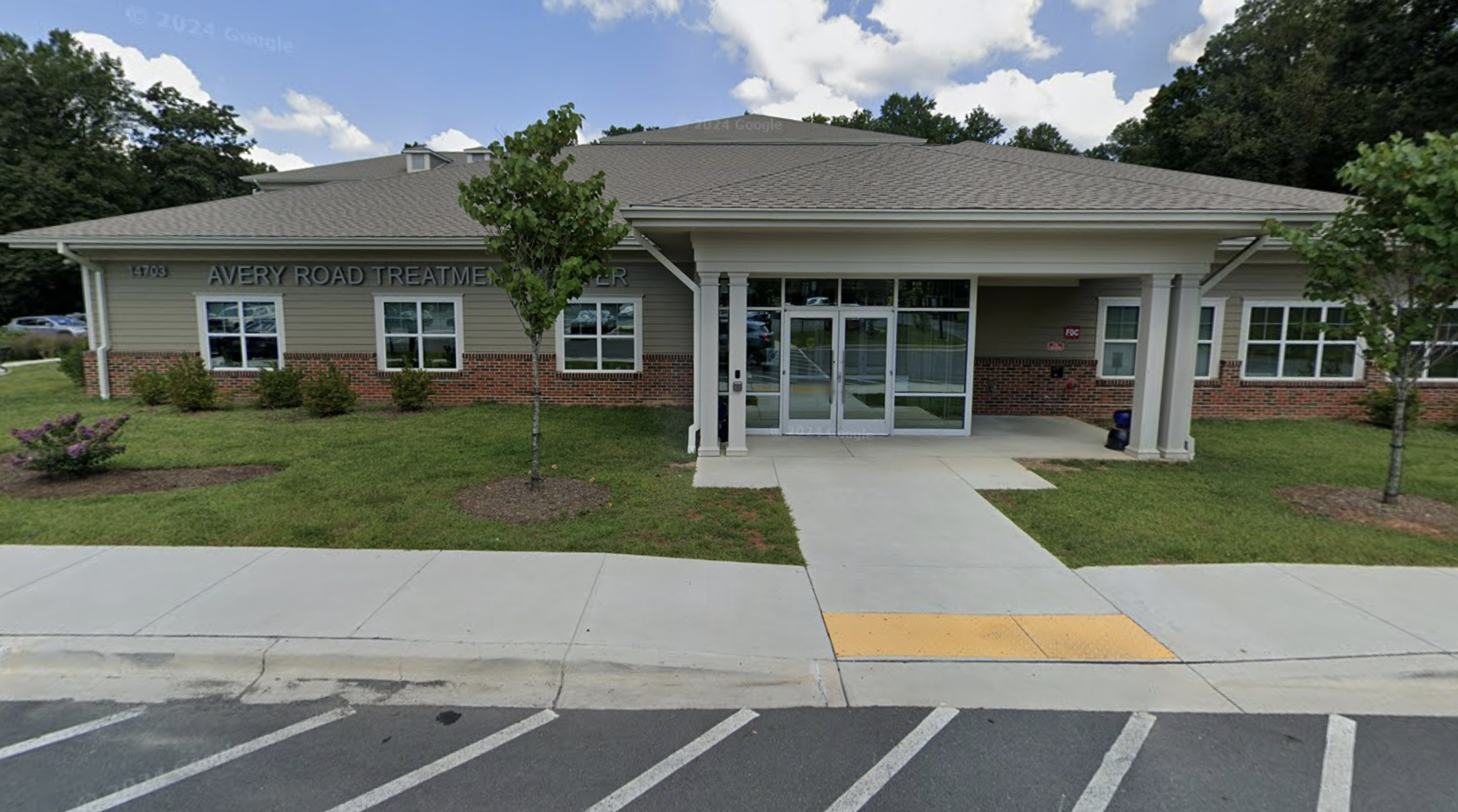 Main entrance of brick building with glass doors and front lawn