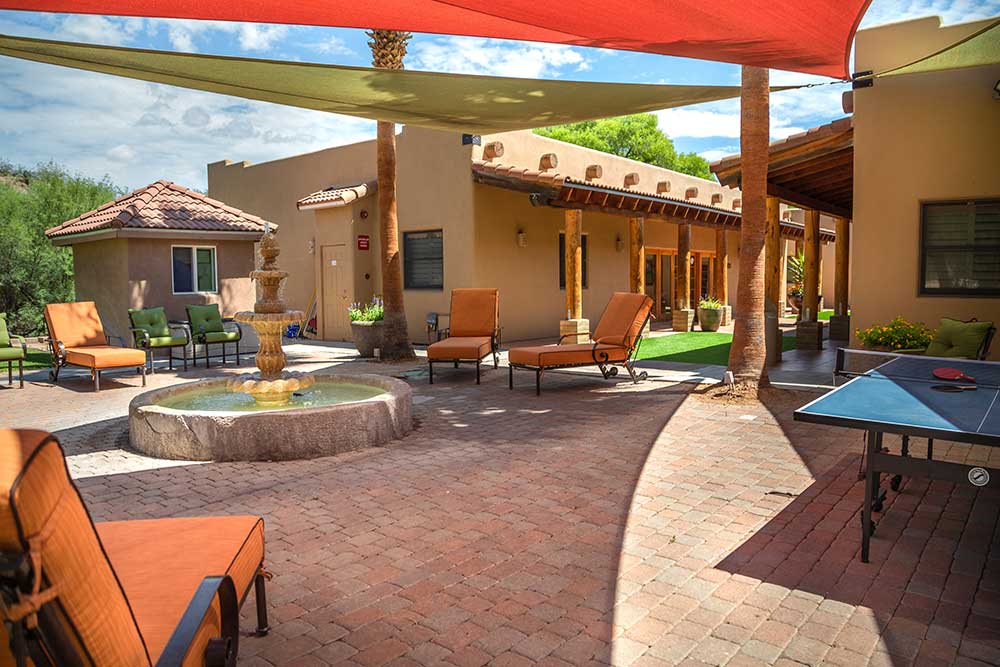 Outdoor patio with lounge chairs, fountain, and ping pong table