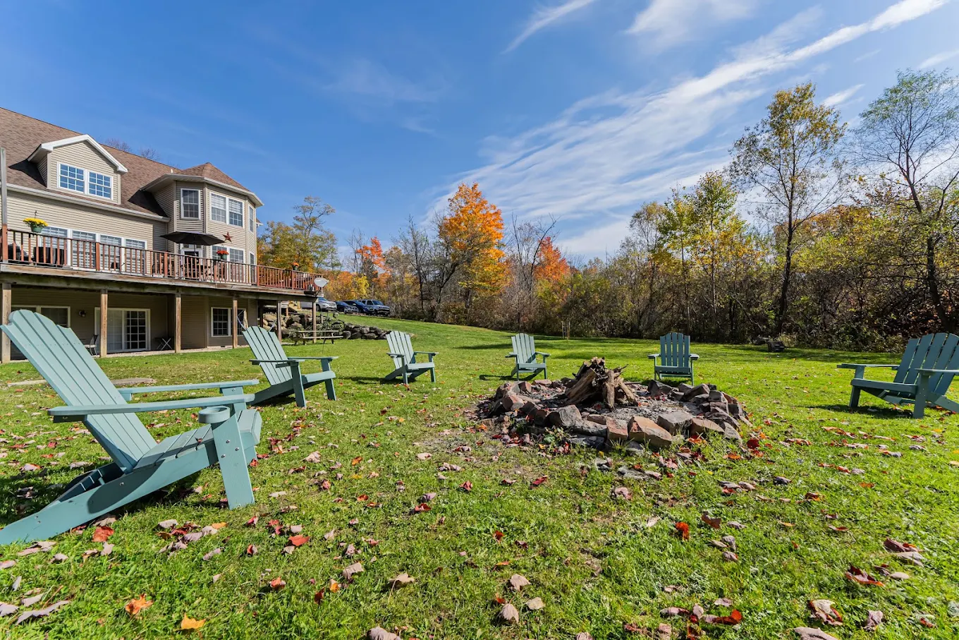 Backyard fire pit surrounded by Adirondack chairs and lawn