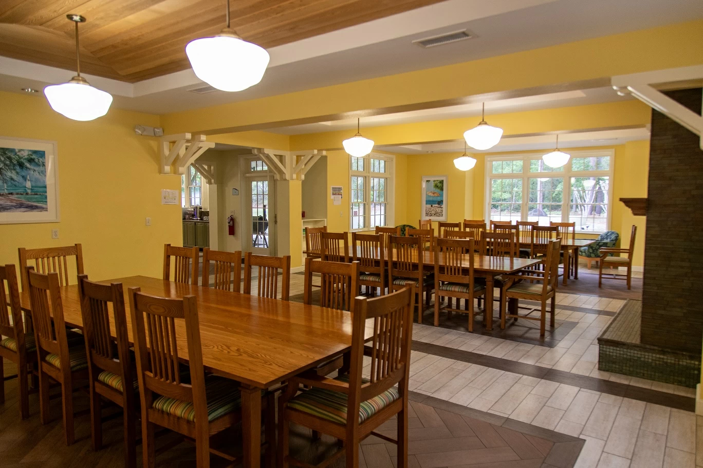 Spacious dining room with wooden tables, chairs, and bright natural lighting inside recovery center