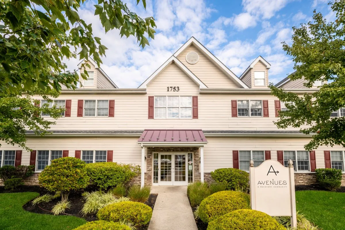 Main building entrance with red shutters and manicured lawn