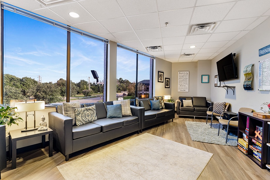Bright lounge area with black couches, TV, and board games