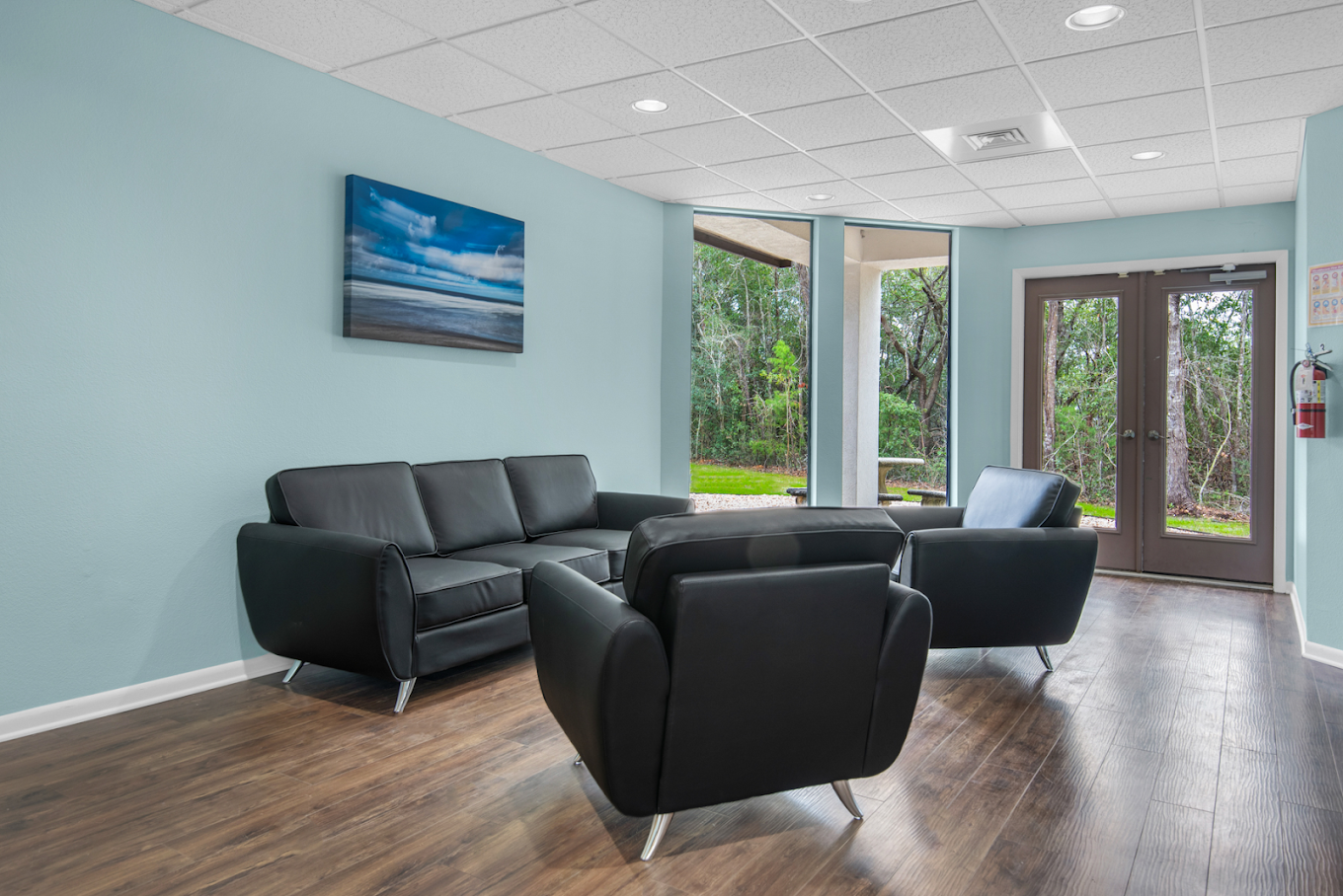 Lounge with black sofas, armchairs, and large windows