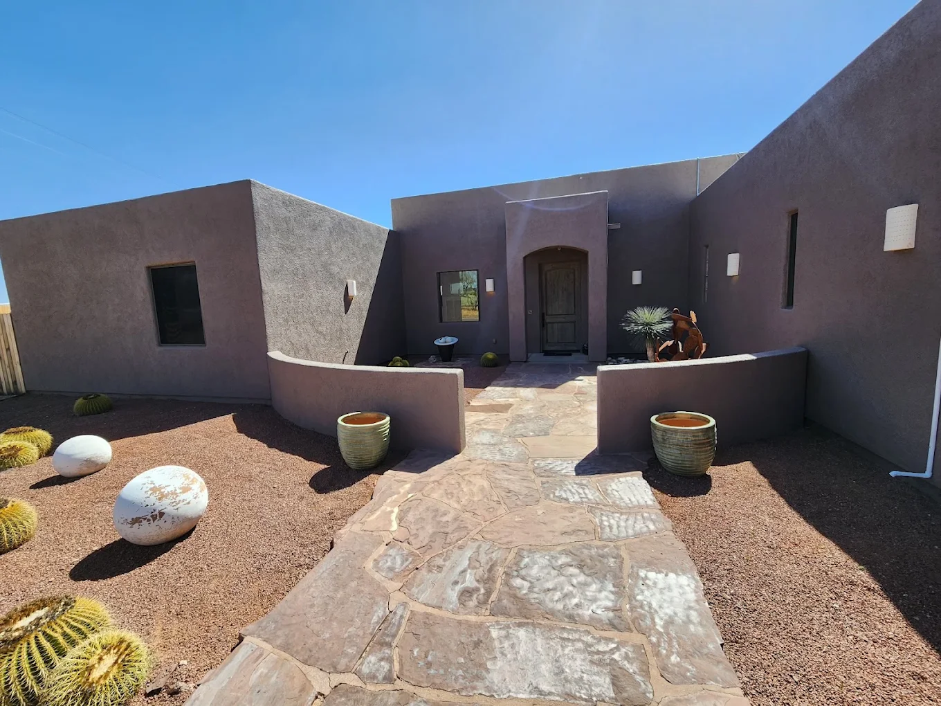 Southwestern-style building entrance with stone walkway, desert landscaping, and decorative planters