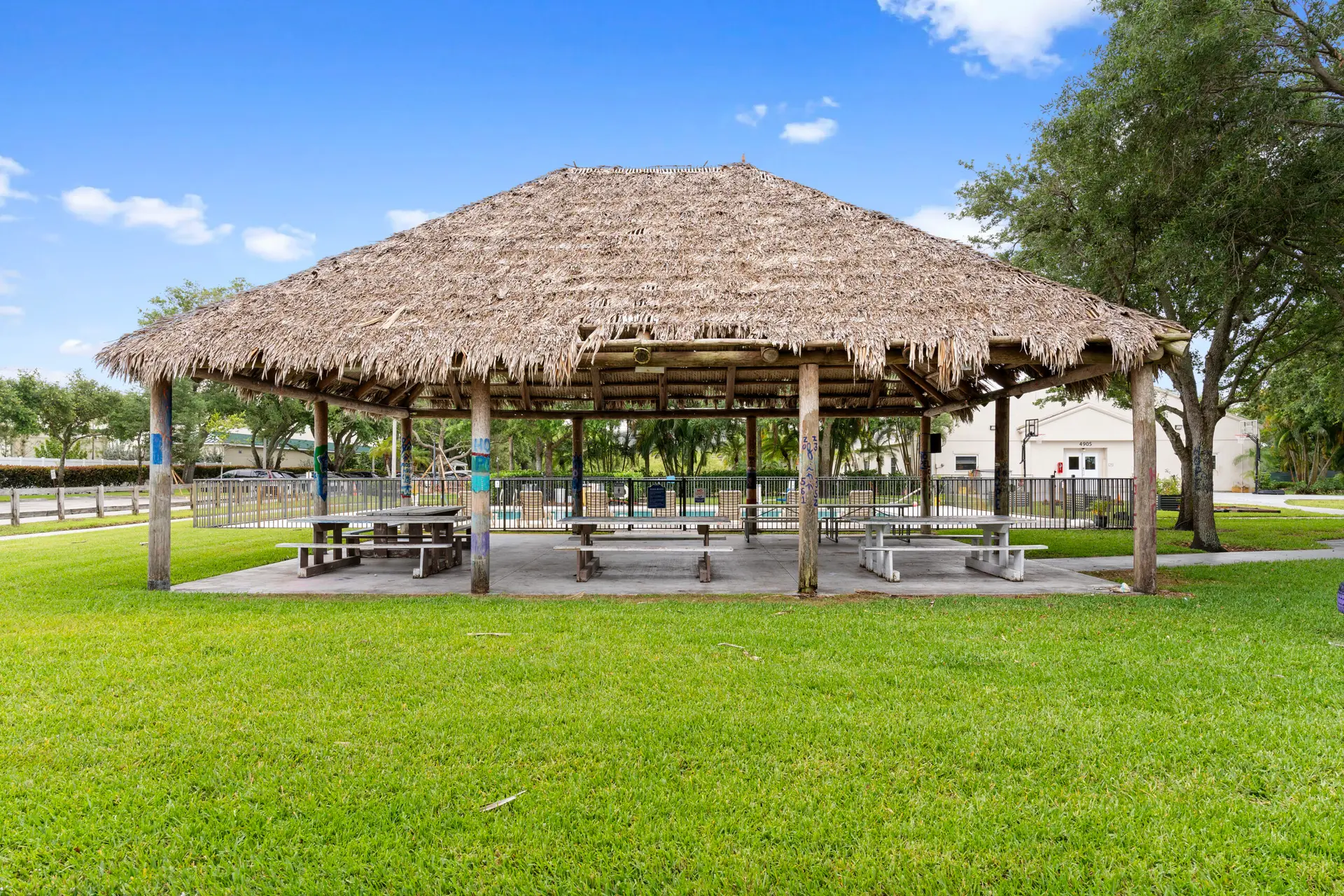 Thatched pavilion with picnic tables on green lawn