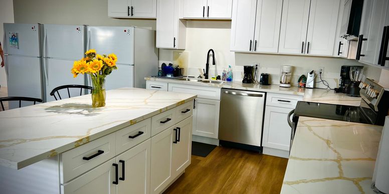 Bright kitchen with island, white cabinets, and appliances