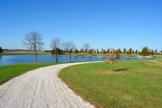 Gravel path curving around pond and grassy field