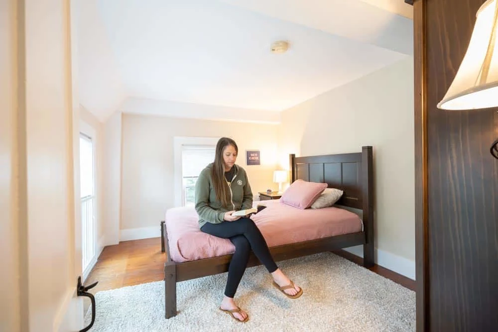 Woman sitting on bed reading in cozy bedroom