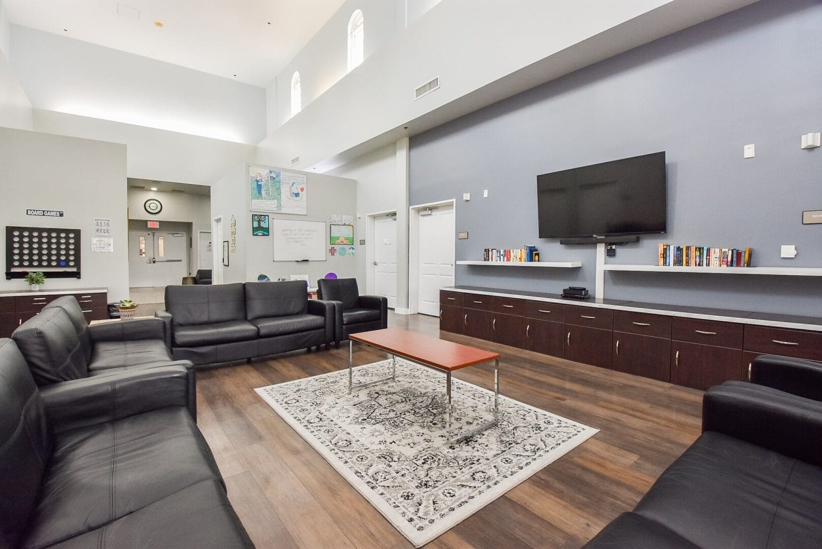 Common room with leather seating, a large TV, and bookshelves.