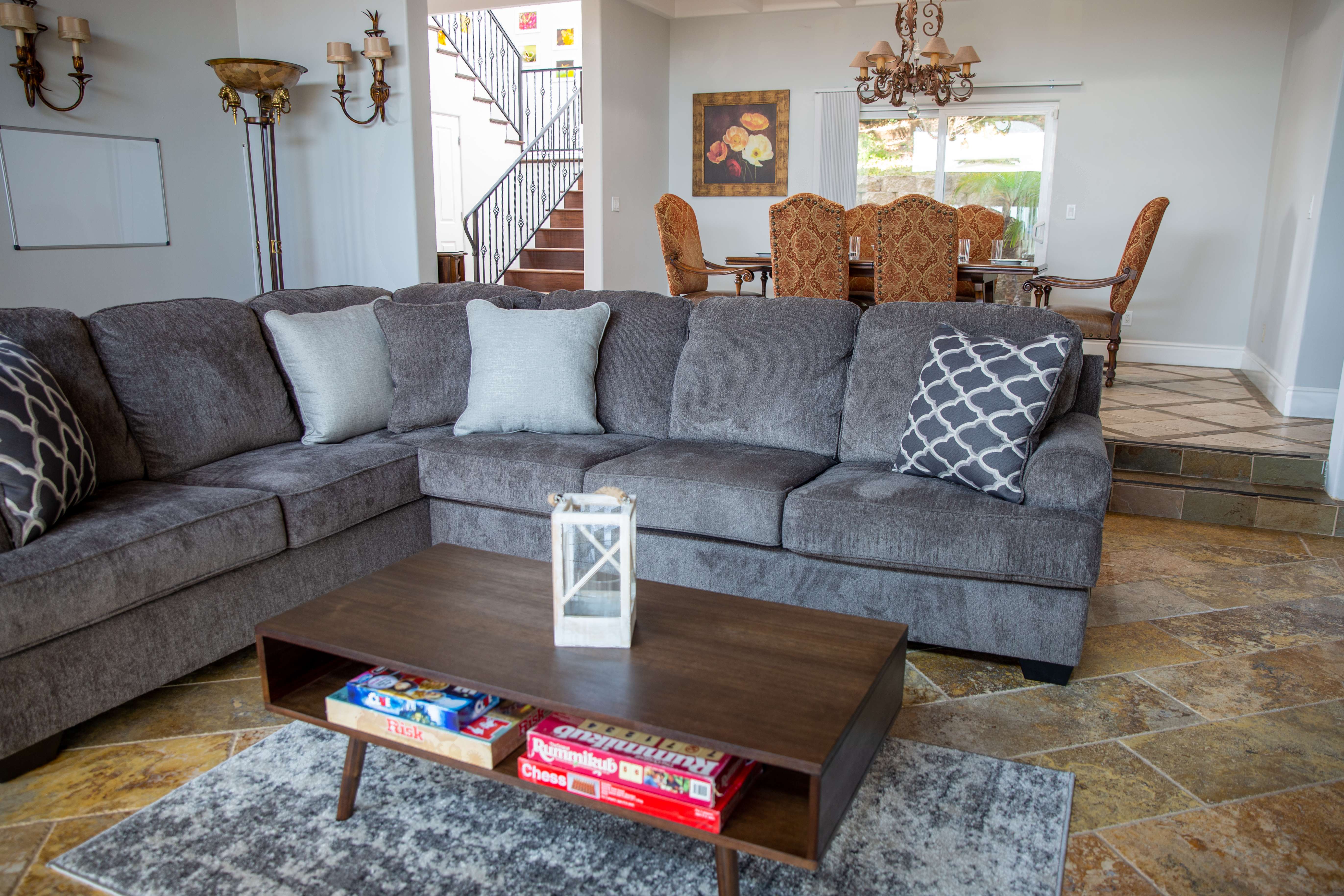 Gray sectional sofa near a formal dining area with ornate chairs