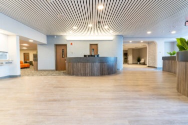 Spacious modern lobby with curved desk and wood flooring.