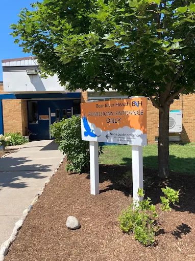 Sign marking admissions entrance beside landscaped walkway