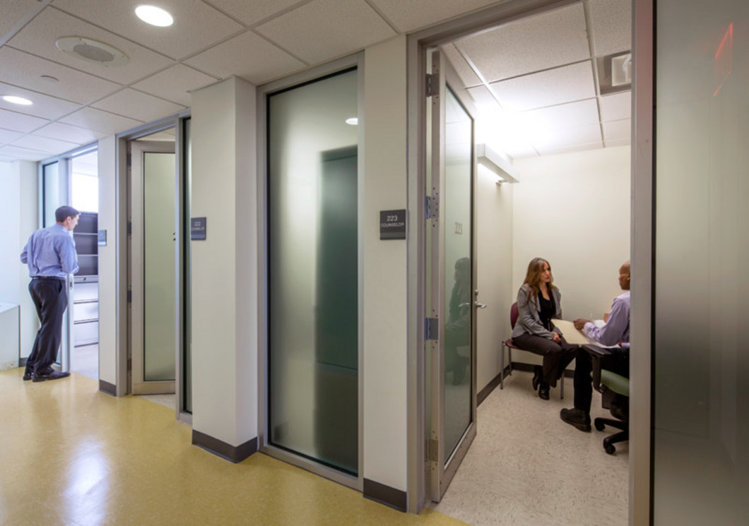 Facility hallway with private rooms and staff members