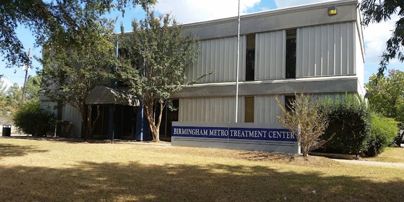 The Birmingham Metro Treatment Center is a two-story building surrounded by trees and a grassy lawn, offering a welcoming and peaceful environment.