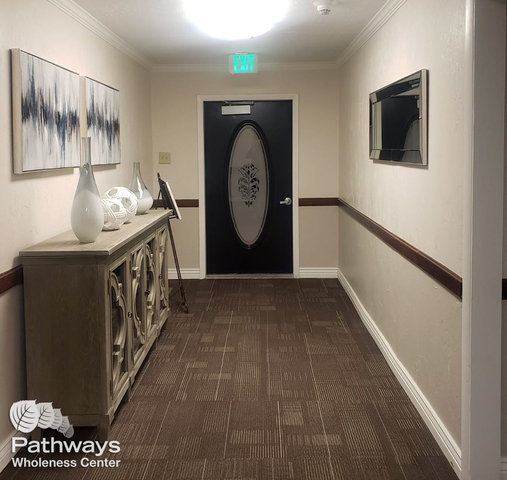 Elegant hallway with decorative console table, artwork, and a door with frosted glass at Pathways Wholeness Center