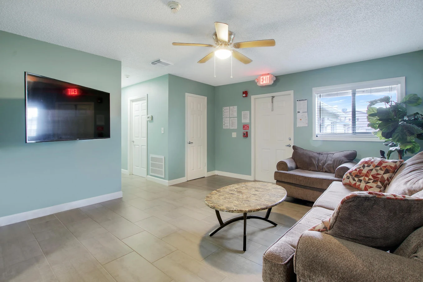 Lounge with sofas, wall TV, and ceiling fan