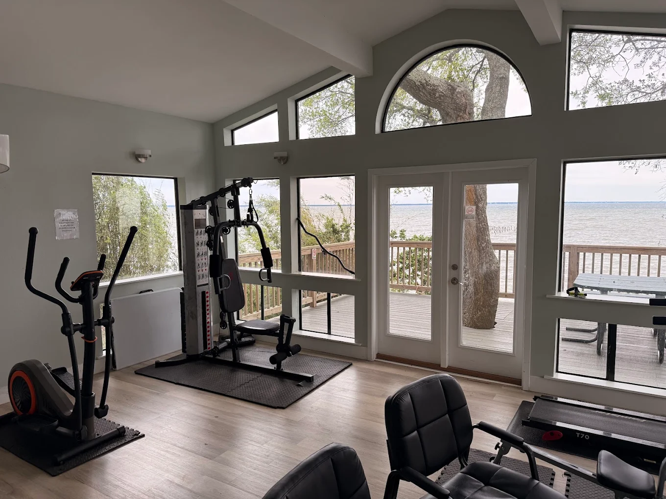 Fitness room with cardio and strength equipment by windows