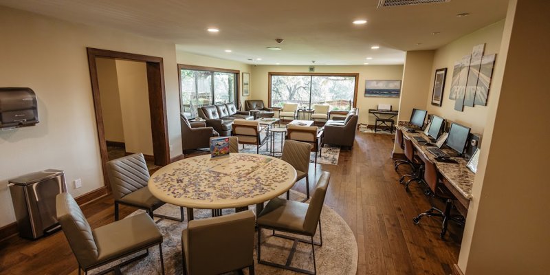  Cozy lounge area featuring a puzzle table, comfortable seating, and computer workstations with a scenic view through large windows.