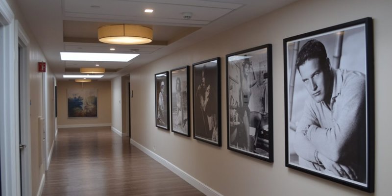 A well-lit hallway with wood floors features framed black-and-white photos of iconic figures, creating a stylish and timeless ambiance.