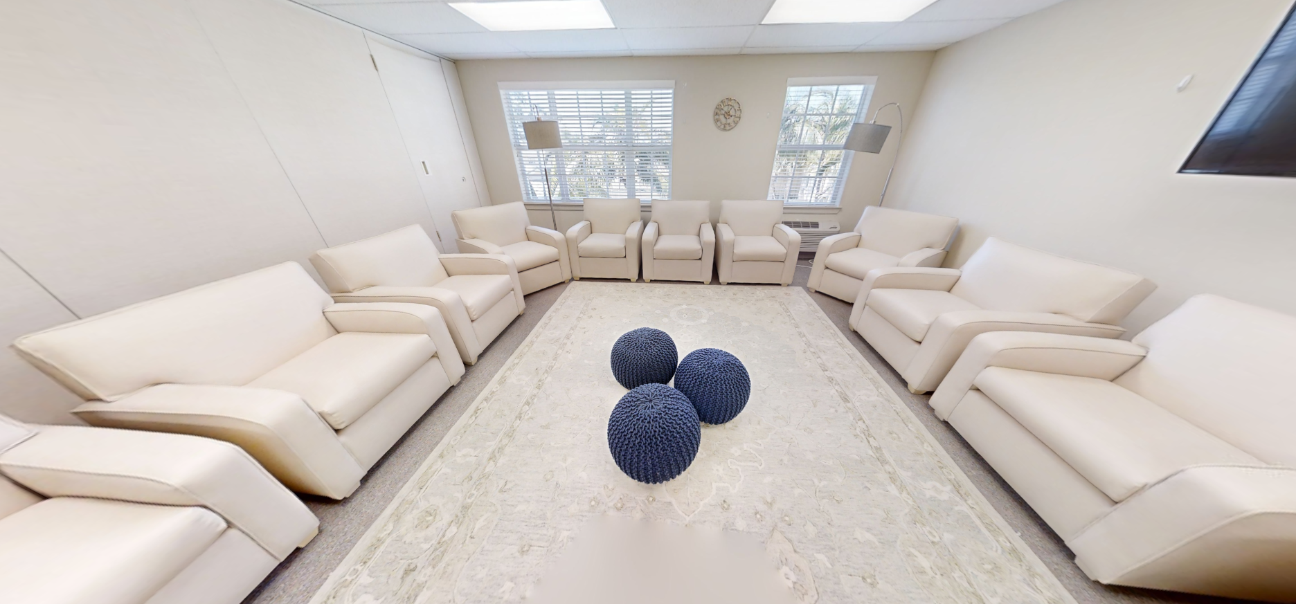 Circle of white chairs in bright therapy room