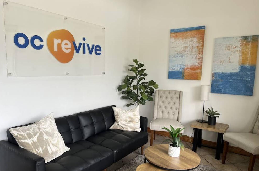 Waiting area with seating, artwork, and OC Revive sign