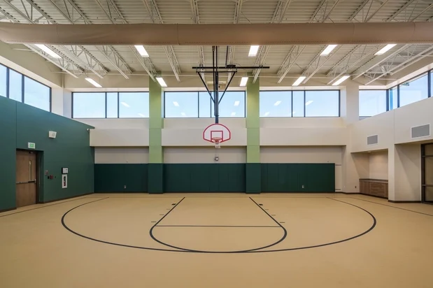 Indoor basketball court with hoop and marked court lines.