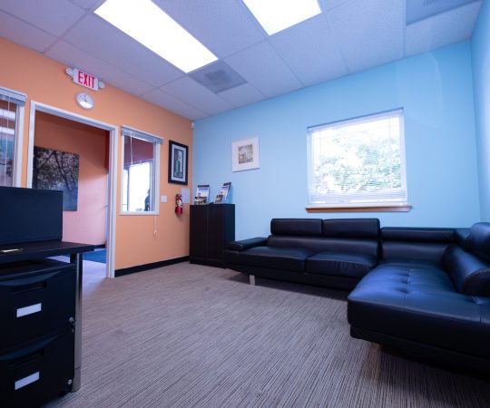 Black leather sectional couches and colorful walls
