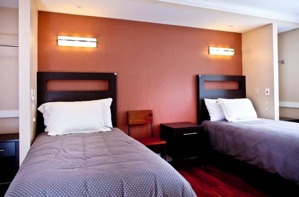Two single beds with modern headboards and wall lights