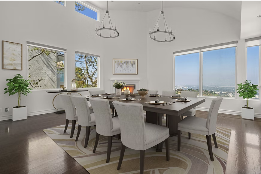 Dining area with long table, high ceilings, and hillside views