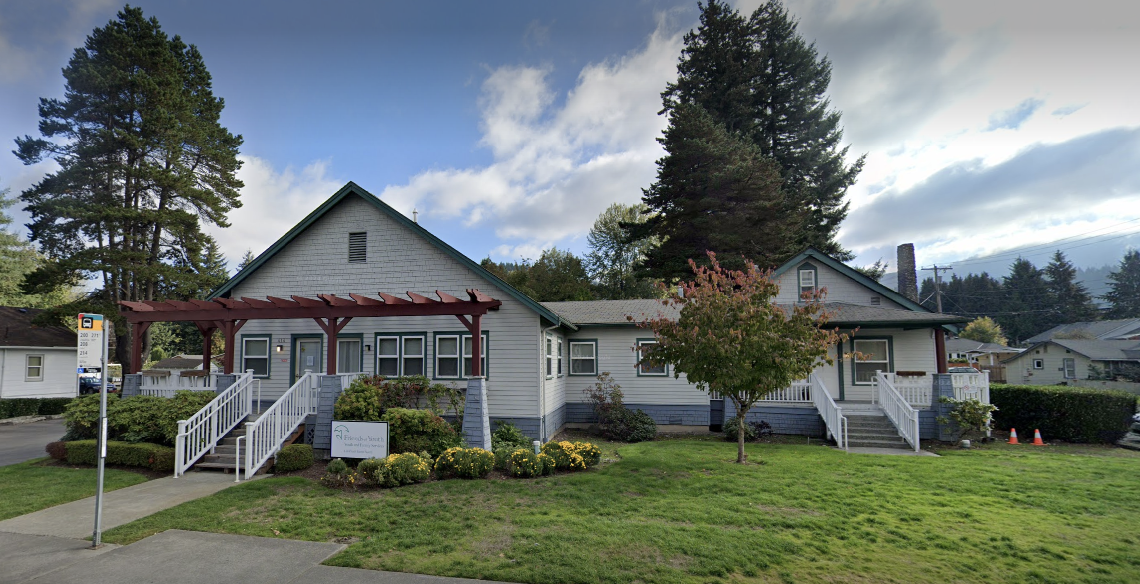 A welcoming building with a large lawn, trees, and a pergola at the entrance, creating a serene atmosphere.