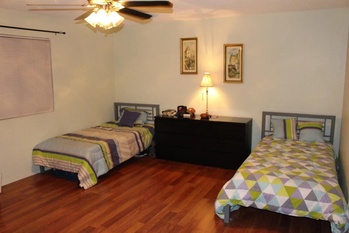 Two twin beds with lamp and wood flooring