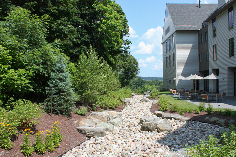 Landscaped grounds with stone creek beside facility