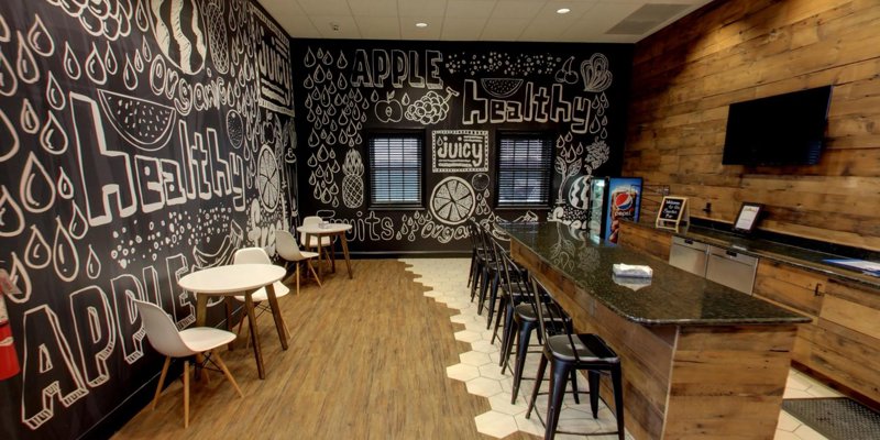 Trendy café-style room with creative chalkboard art, cozy seating areas, a long granite counter, wood accents, and a vibrant atmosphere.