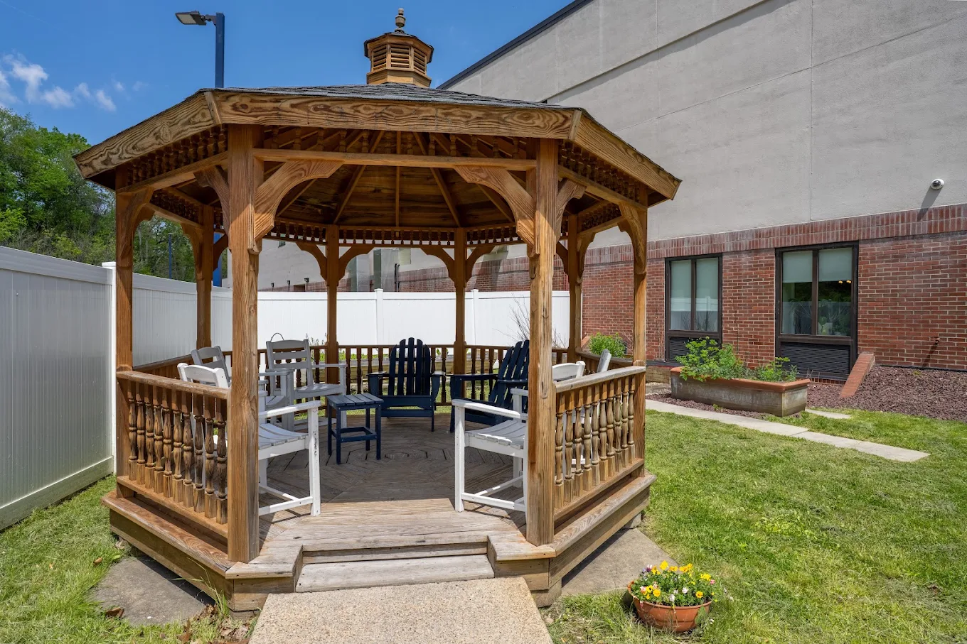 Wooden gazebo with chairs in a grassy outdoor area