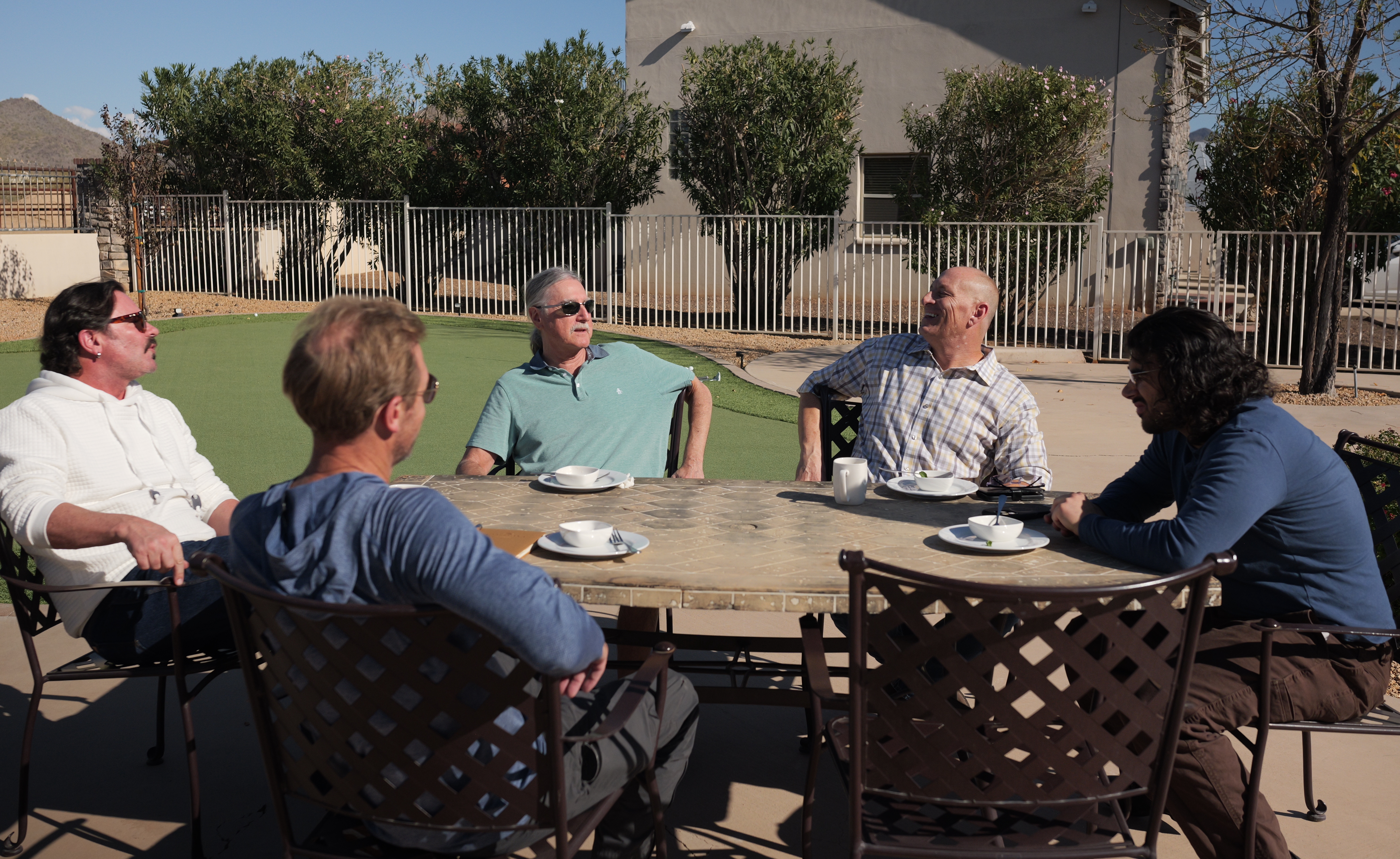 Group of men enjoying conversation at outdoor dining table