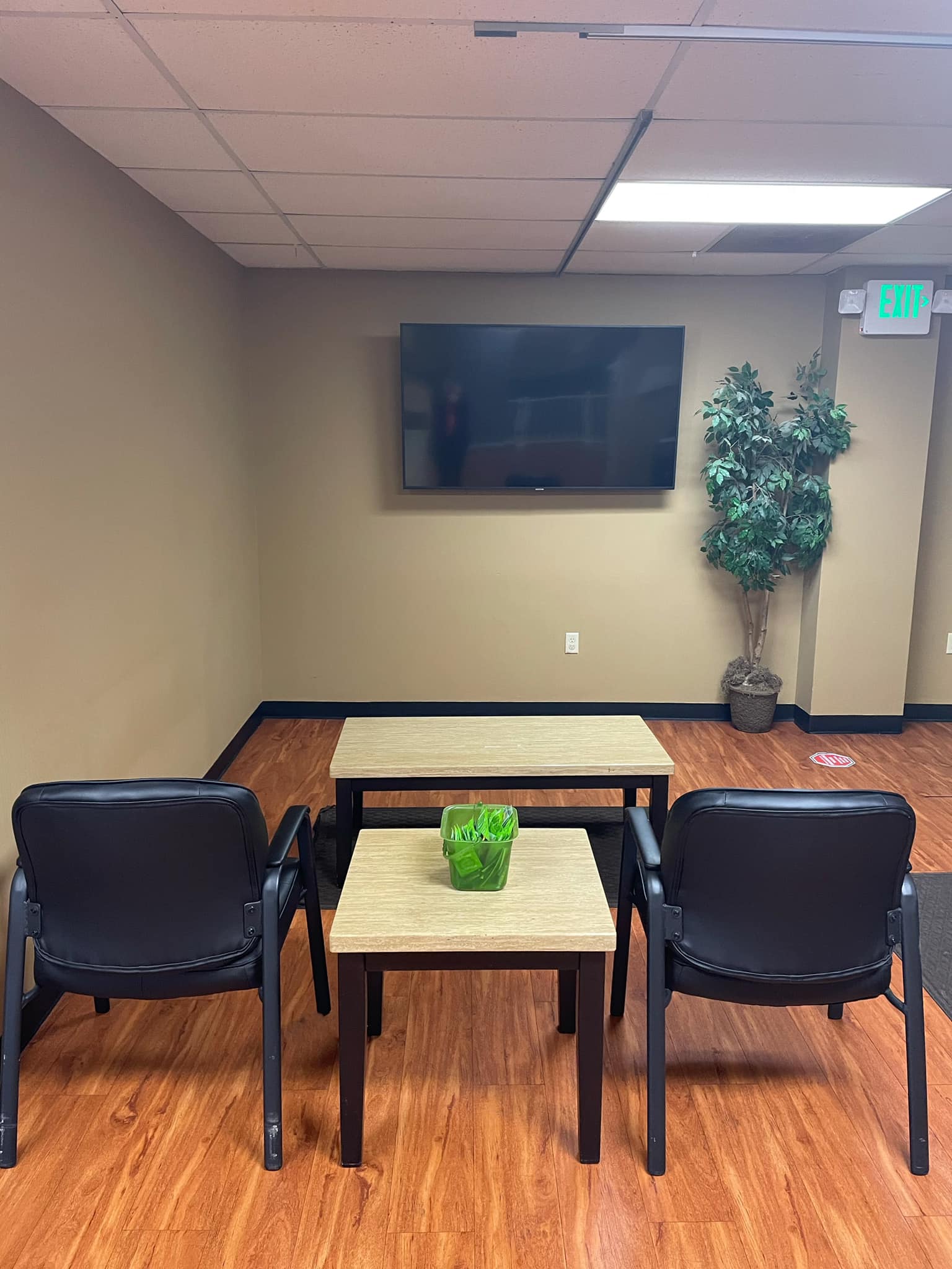 Small corner seating area with chairs, tables, and mounted TV