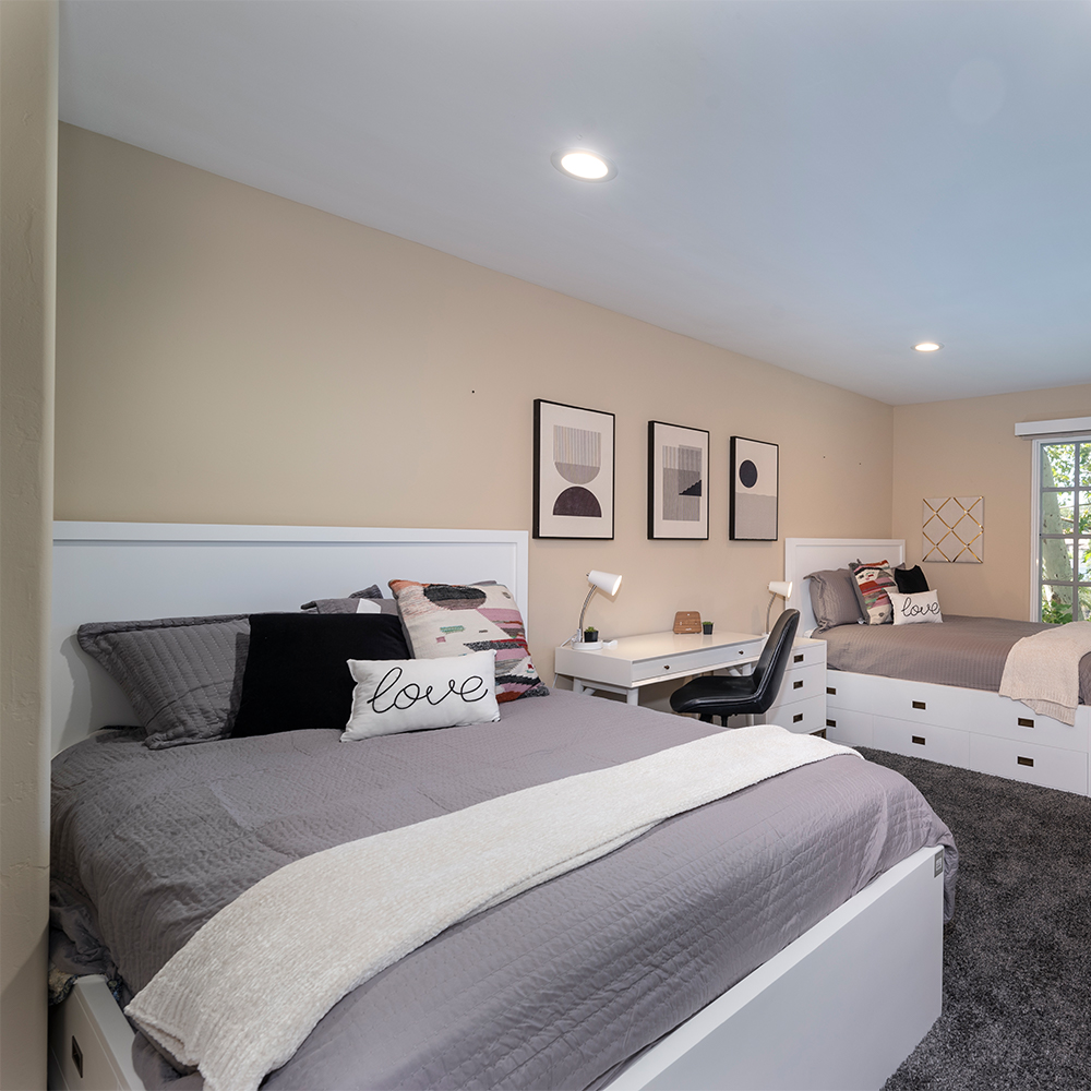 Shared bedroom with two beds and a desk.