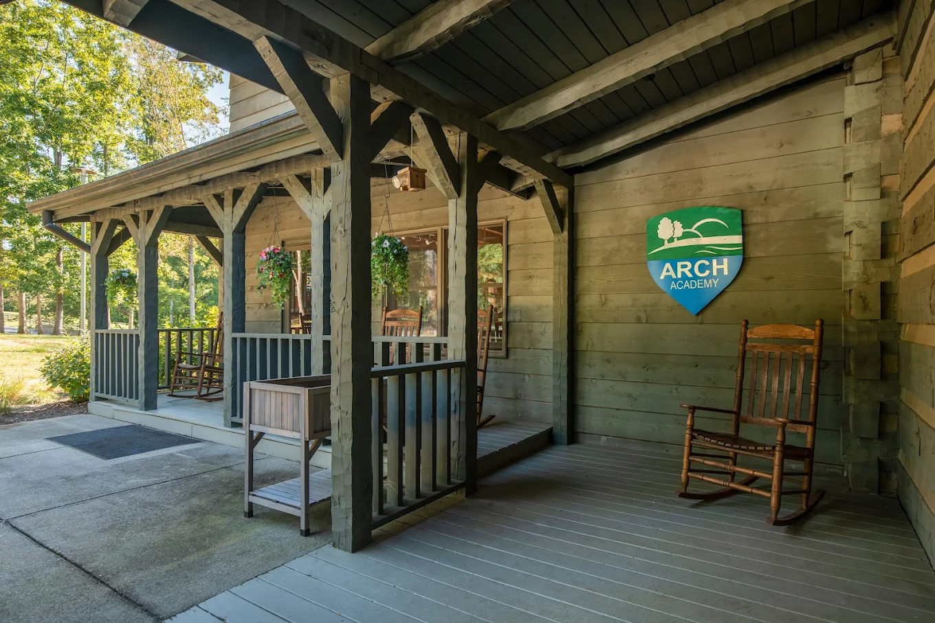 Rustic front porch with rocking chairs at ARCH Academy campus.