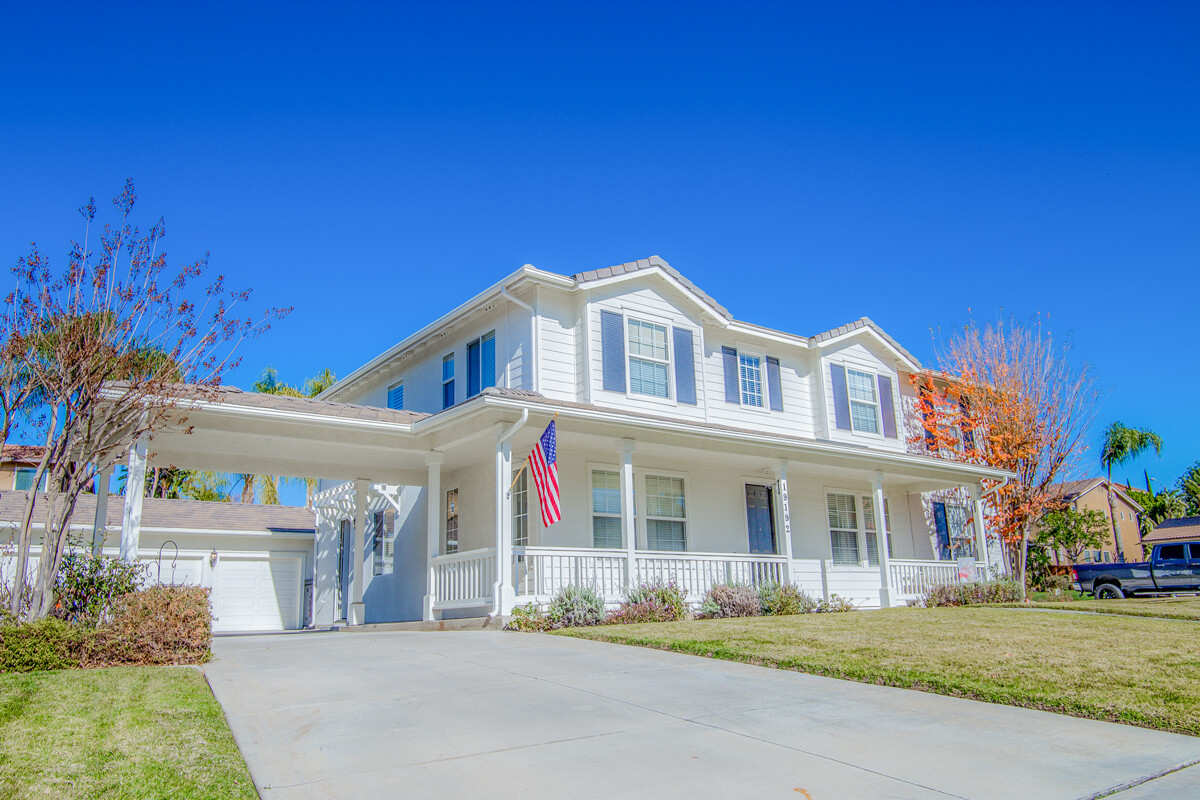 White two-story house with American flag and driveway