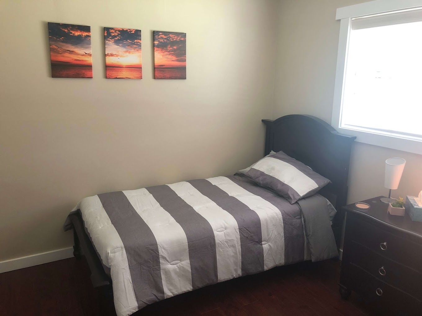 Single twin bed with lamp and scenic artwork