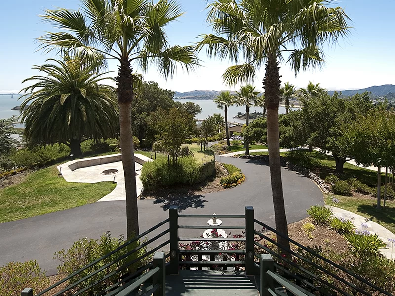 Landscaped grounds with palm trees and view of water and hills