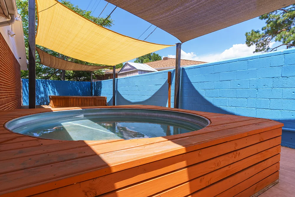 Outdoor hot tub on wooden deck under shaded patio canopy