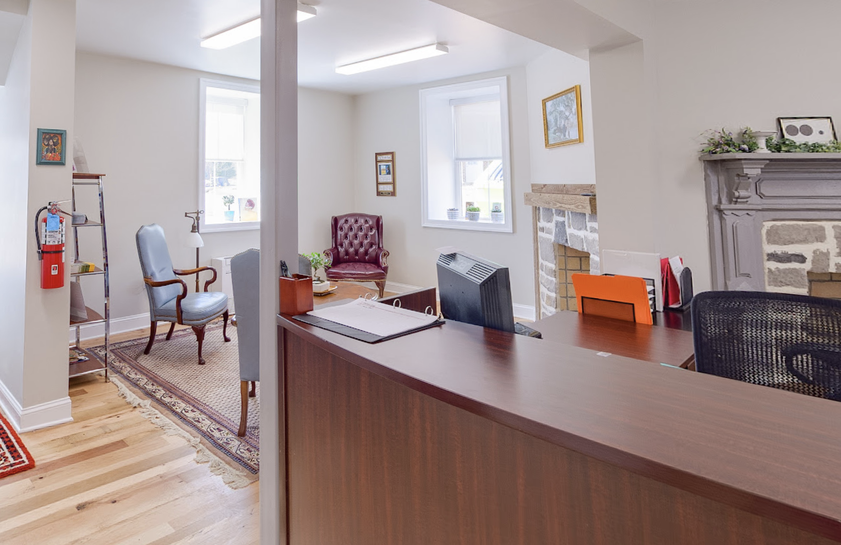 Reception area with wooden desk, armchairs, and fireplace