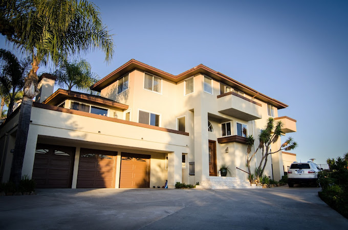 Open wooden front door leading to carved console and decor